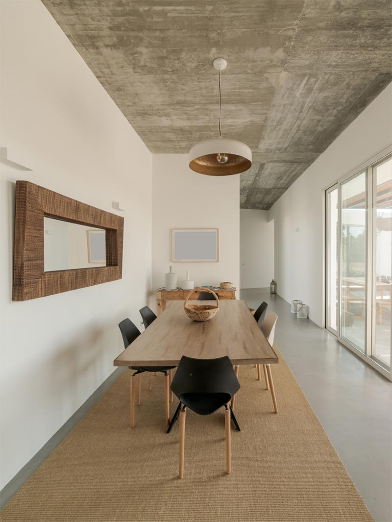 Contemporary dining room with minimalist decor and raw concrete ceiling.