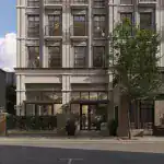Hotel building with modern classic architectural style, grey brick façade, large windows, and balconies, landscaped ground floor entrance, ambient lighting.