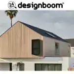 Modern minimalist house with wooden and stucco exterior, gabled roof, large windows, and surrounding trees.